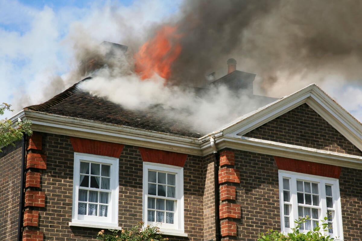 Fire and smoke on roof of brown, single-story brick house