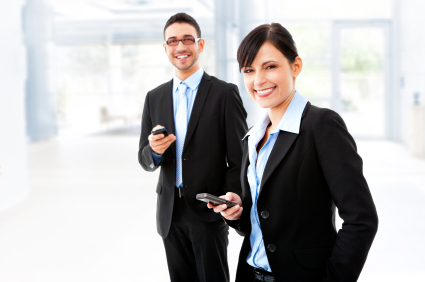 Two young business people holding mobile devices and smiling