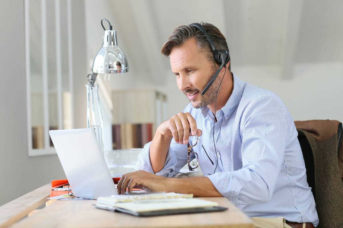 A man working from home using a computer and a headset