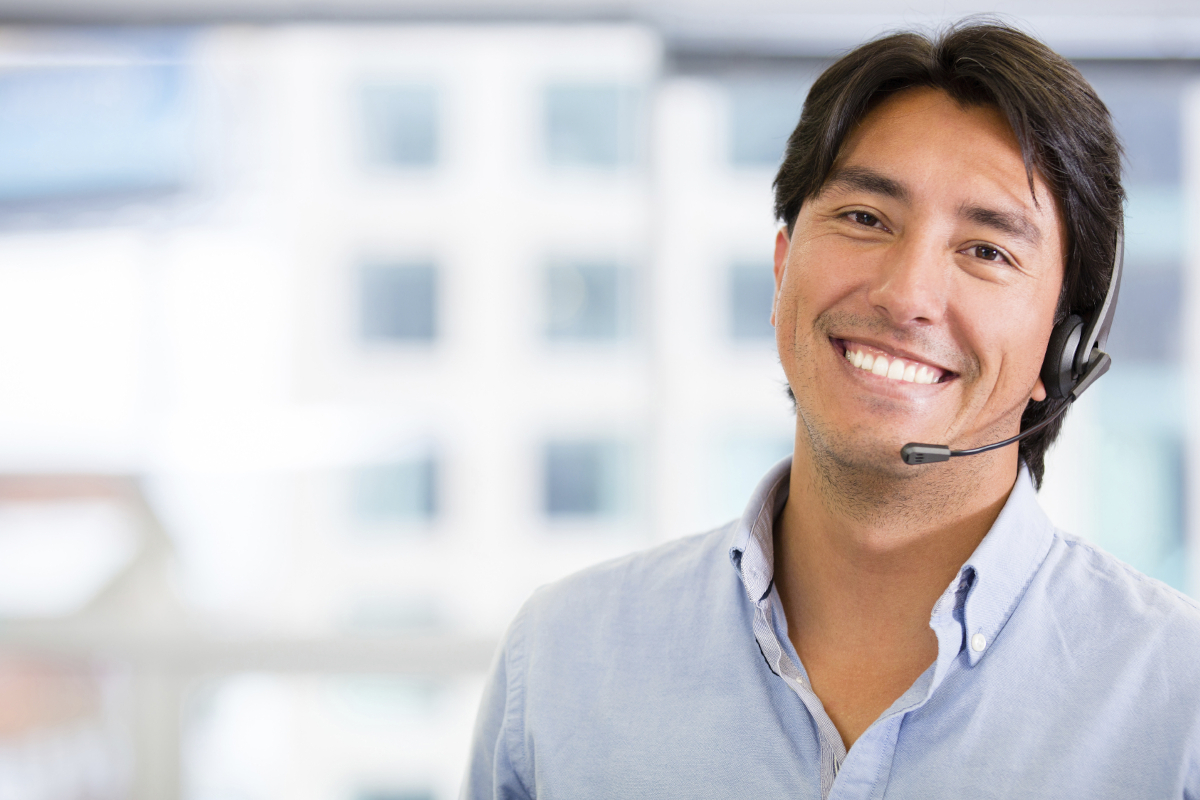 A smiling person with an office desk phone headset on