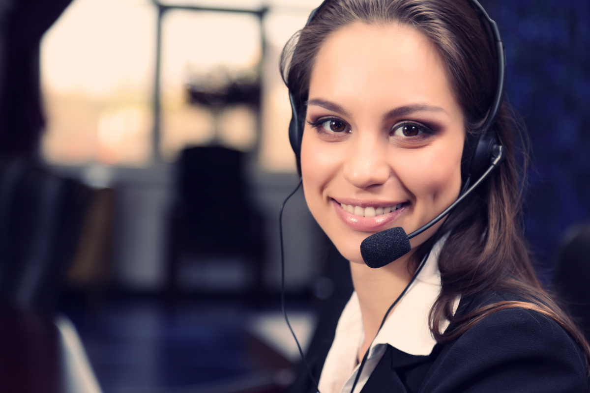 A female help desk employee wearing a headset and smiling