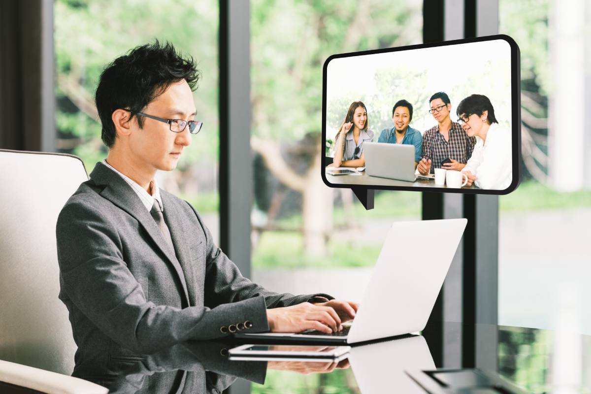 A man working from home and in a video conference with employees at the workplace