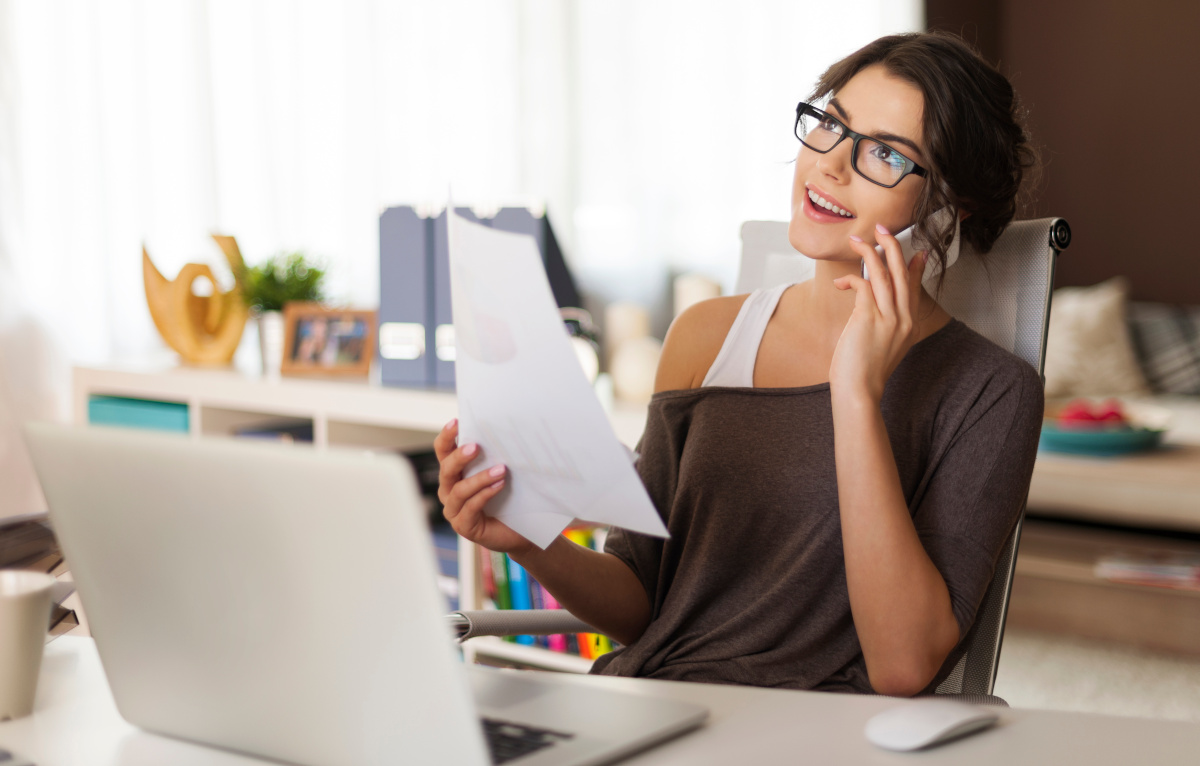 A brunette woman working from home and talking on her cellphone