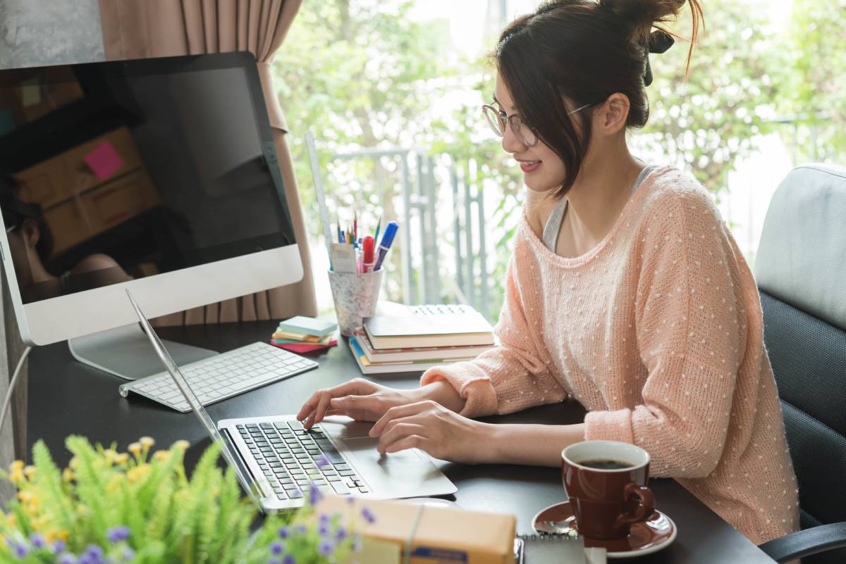 A woman working from home using a laptop at her desk