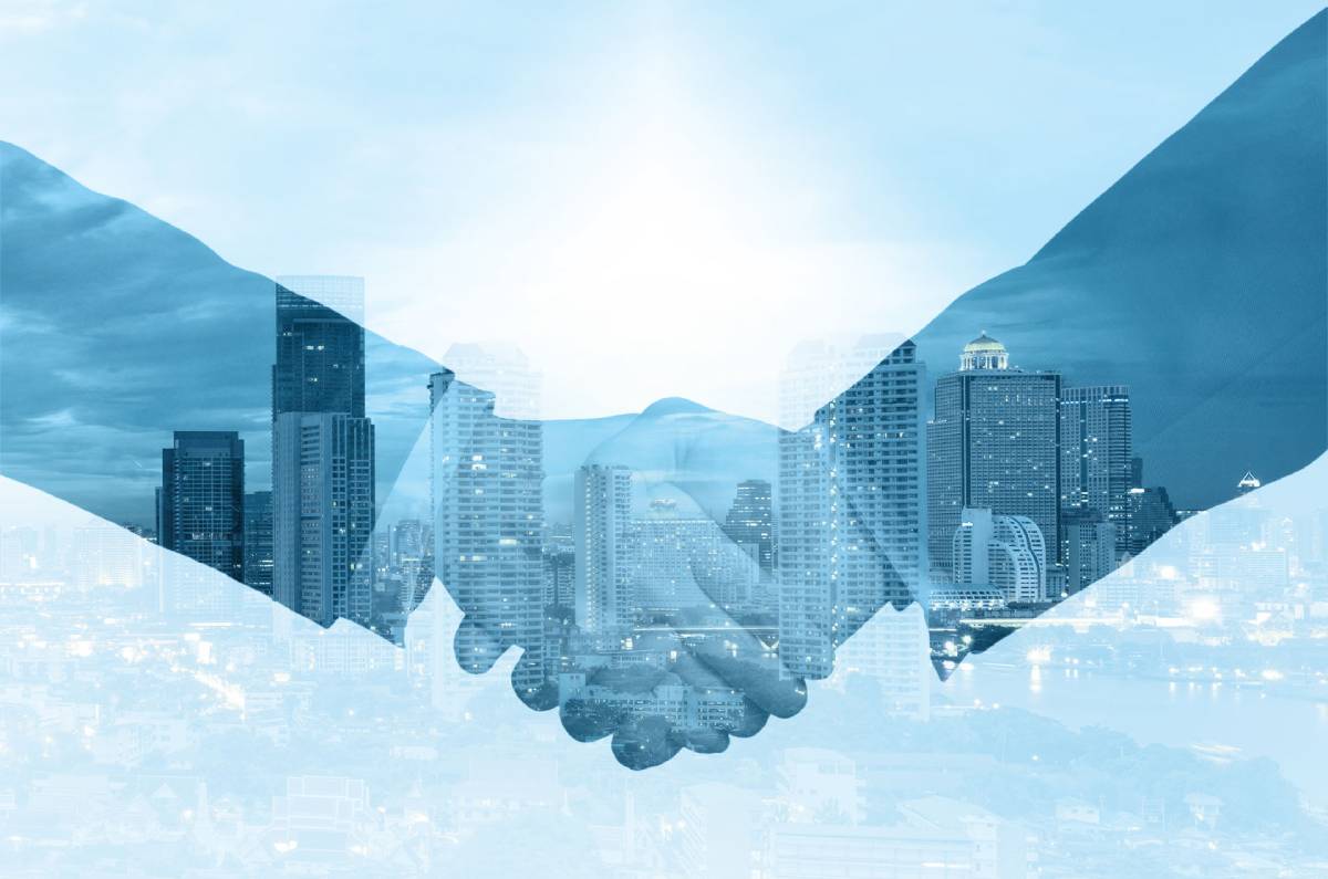 Two businessmen shake hands on a blue background that has a city skyline