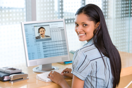 Woman looking over her shoulder while typing on a white computer at her desk