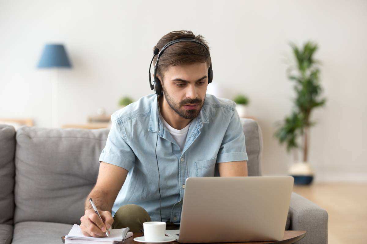 A man working at home using a laptop and a headset