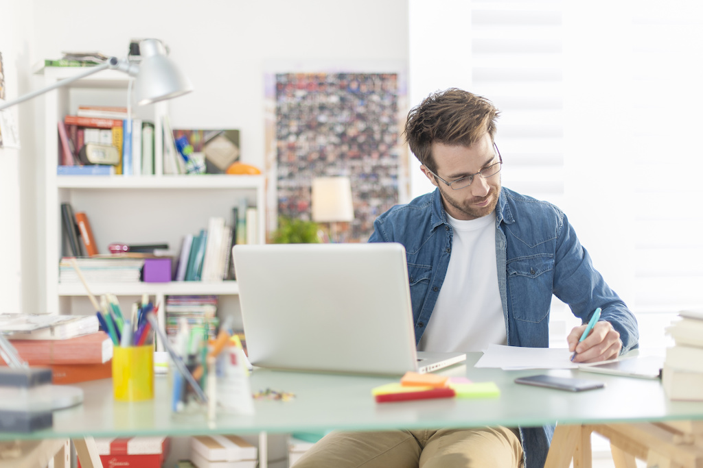 Young man remote working on laptop in home office