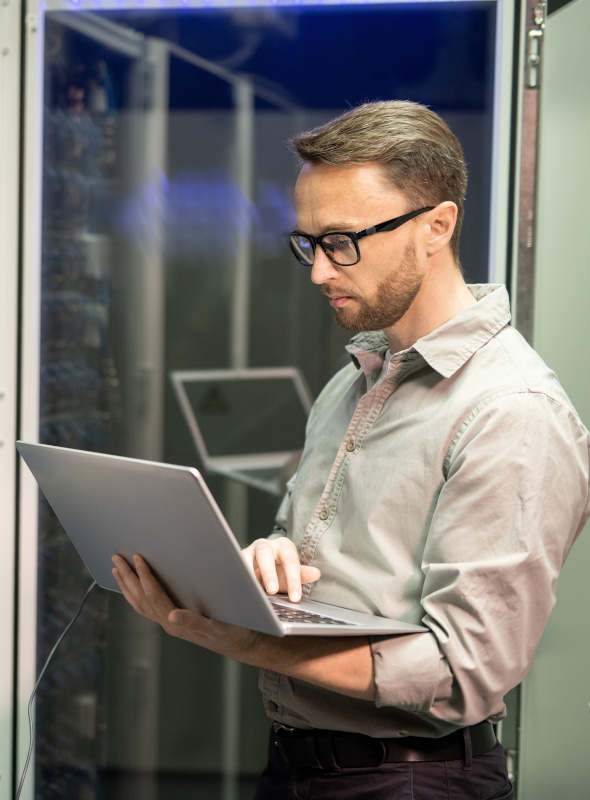 IT Technician Working on Laptop Computer in Network Server Room